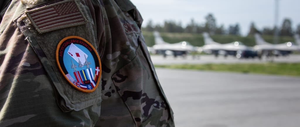 Ace-märket på amerikansk deltagare framför uppställda F-16 på Luleå Kallax flygplats under Arctic Challenge Exercise 2019
