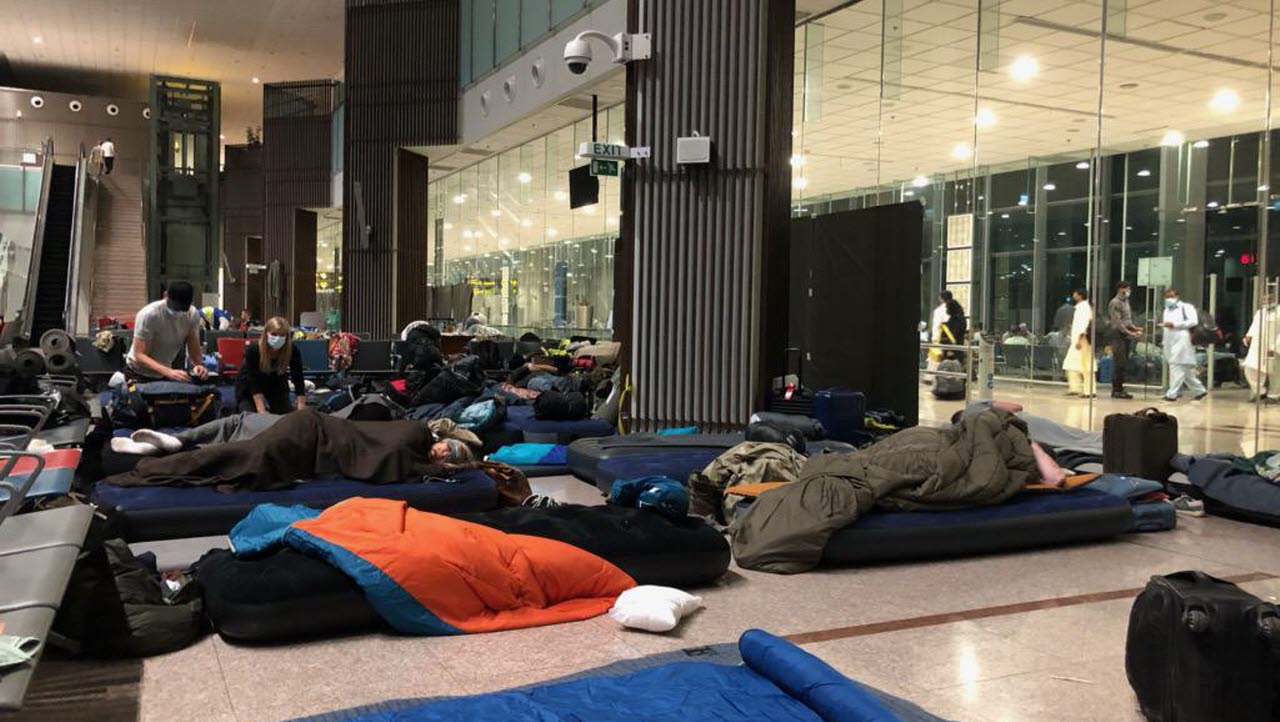 Personer sover på golvet i en flygplatsterminal.