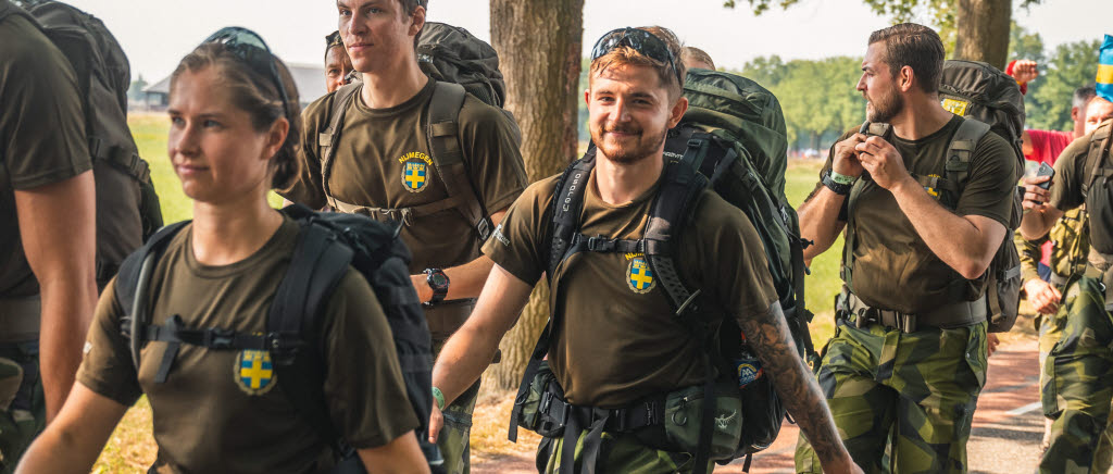 Svenska soldater i kamoflage marscherar. Det är soligt ute. 