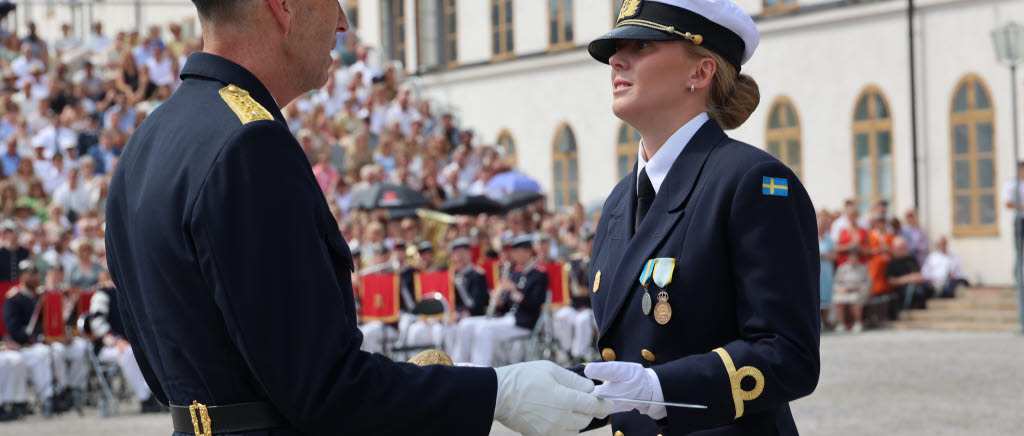 Fänrik  Clara Berg tar emot Forna Karlbergares hederssabel ur ÖB:s hand. Denna utmärkelse är den finaste som delas ut under ceremonin och ges till bäste kamrat och röstas fram av kursens deltagare. Examen för Försvarshögskolans officersprogram på Militärhögskolan Karlberg framför Karlbergs slott för 229:e kursen. Kadetterna är i och med detta fänrikar.