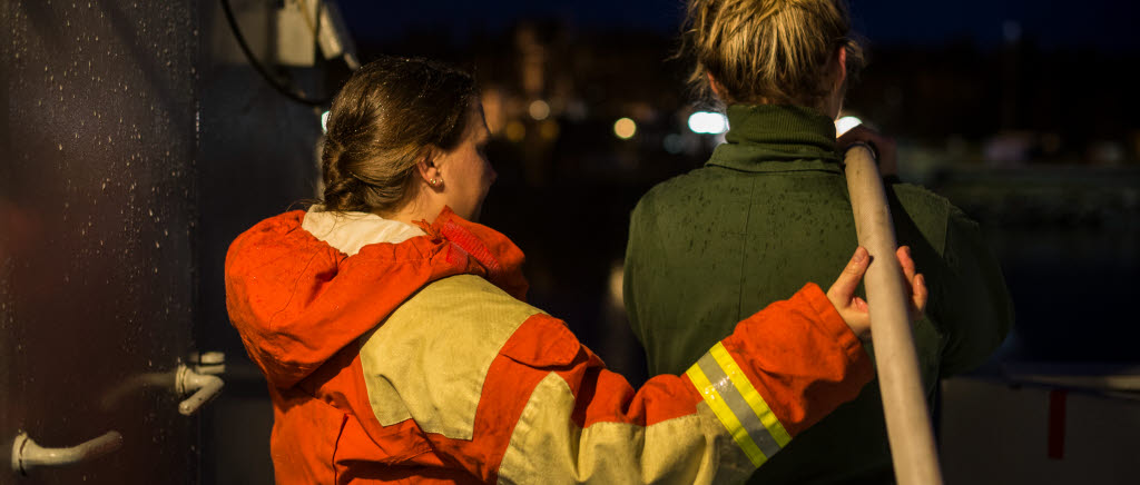En rökdykare förevisar hur brandslangen fungerar.