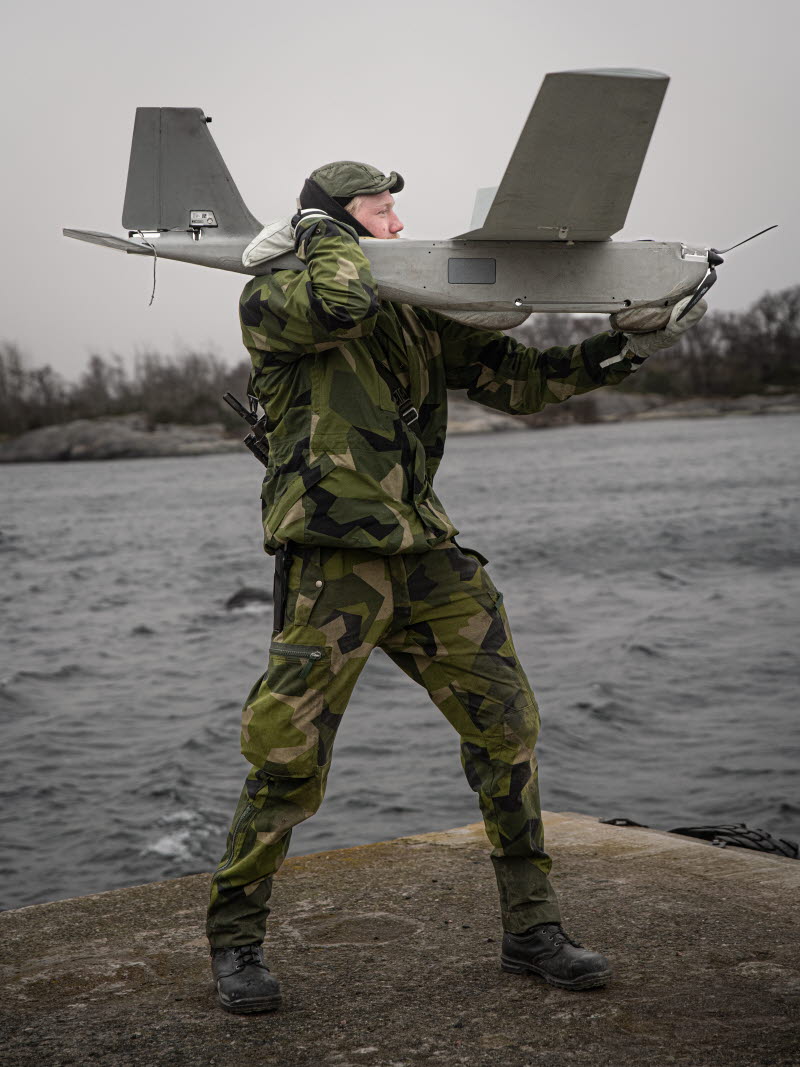 Soldat som står på en klippa framför vattnet.