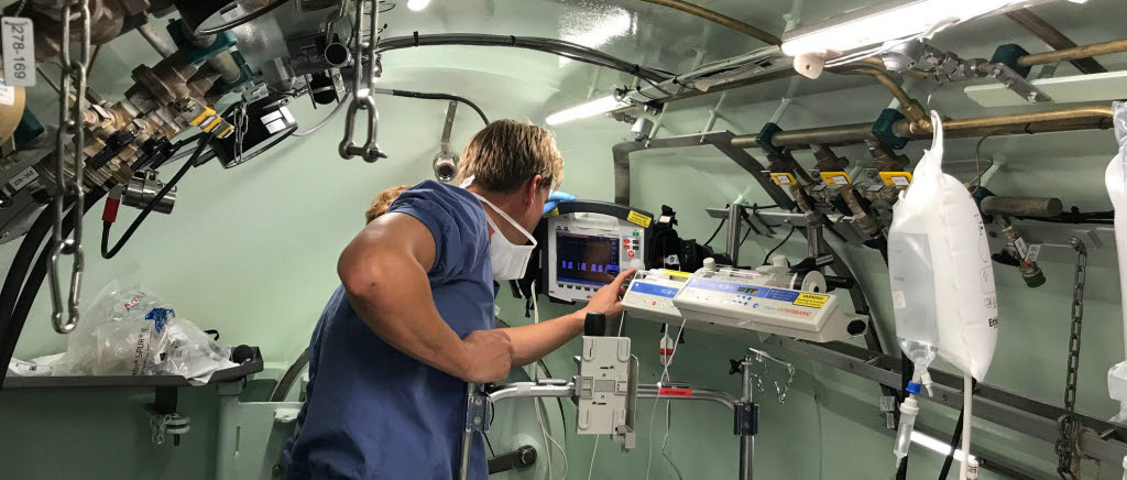 
Här är foton från tryckkammaren där en patient förbereds för tryckbehandling inne i kammaren. Med förberedelser, en timmes behandling och återställning är patienten på plats i cirka 3 timmar.
Utanför finns operatörer som hela tiden övervakar utrustningen.