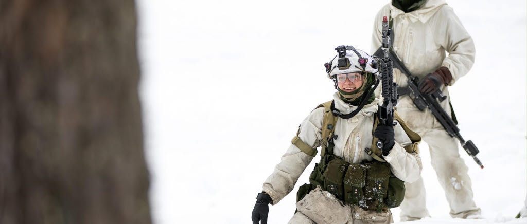 Soldater i vinterlandskap. De är klädda i snöblusar och bär på vapen. 