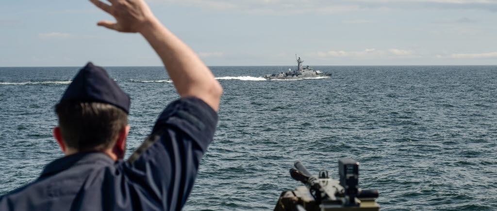 Fartygschefen på HMS Härnösand hälsar på HMS Gävle när fartygen byter av varandra någonstans på Östersjön. 