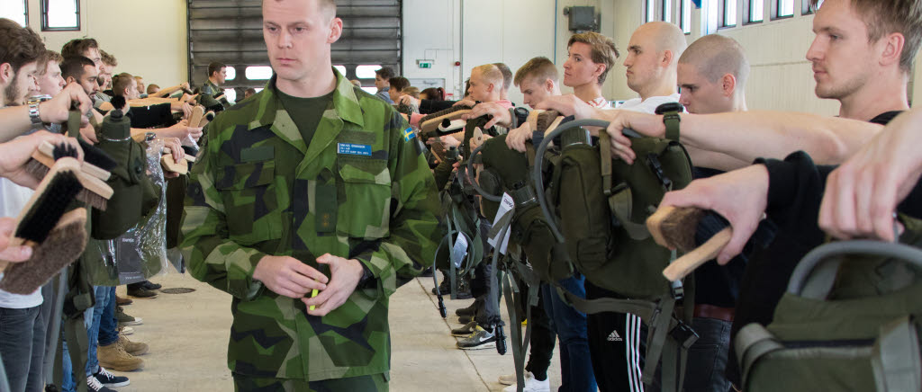 Rekryterna håller fram materiel med raka armar enligt order medan fanjunkare Mikael Eriksson inspekterar. Det gäller att ha koll på sin tilldelade utrustning och veta vad som är vad.
