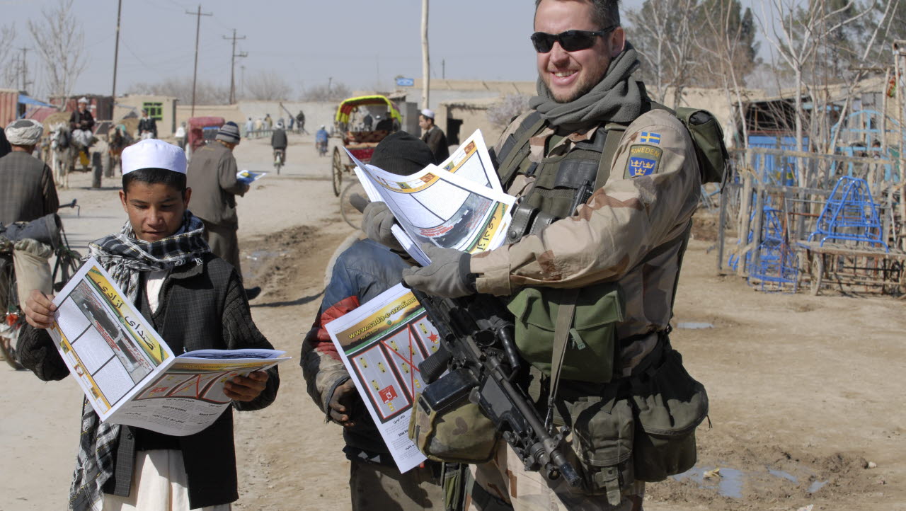 En soldat ur ett Taktiskt Psyops Team (TPT) distribuerar ISAF News. Tidningen har många visuella budskap och bilder för att kunna nå fram även till lågutbildade och illiterata målgrupper. Bilden är en del av forsvarsmakten.se/varhistoria. 
