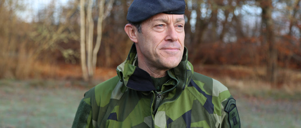 Nye chefen Militärregion Mitt överste Thomas Karlsson står och tittar mot sitt vänster framför en skigsdunge. Klädd i basker.