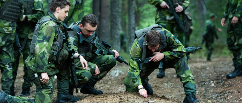 En grupp förbereder sig inför stundade uppgift genom att rekognosera i terrängen och diskutera.