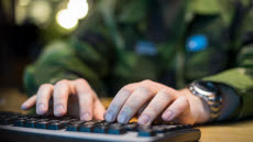 Cybersoldat skriver på ett tangentbord vid dator.