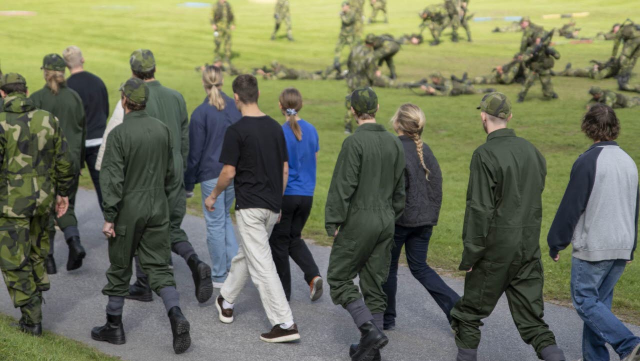 Civila och soldater vandrar ute på fält