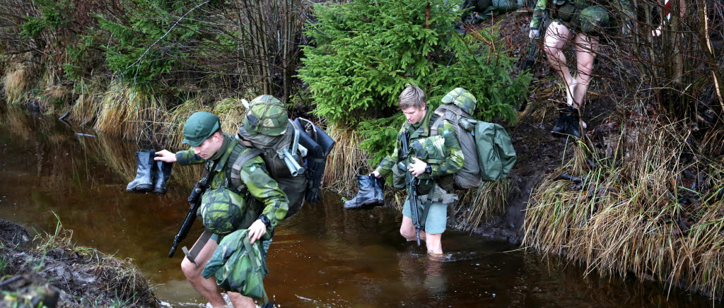 Kadetter vadar över ett kallt och strömt dike. En del av övning Ihärdighet 18. Kadetter från Militärhögskolan Karlberg.