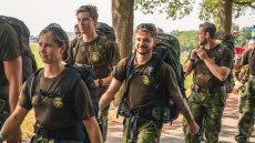 Svenska soldater i kamoflage marscherar. Det är soligt ute. 
