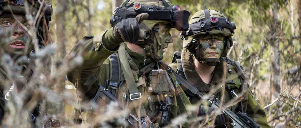 Tre stridsberedda soldater i terrängen