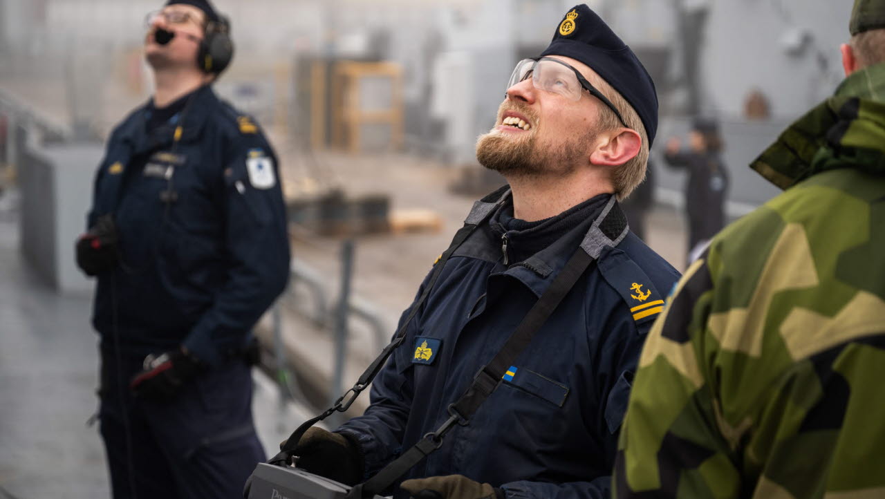 mman ligger tät över Berga. Det välbekanta mullret från korvetternas och stridsbåtarnas motorer inne i örlogshamnen har fått sällskap av ett nytt ljud. Det kommer från en liten farkost som surrar ovanför däck på korvetten HMS Gävle. Det är första gången i flottans historia som det obemannade flygande systemet manövreras av en besättningsmedlem på marinens fartyg. 