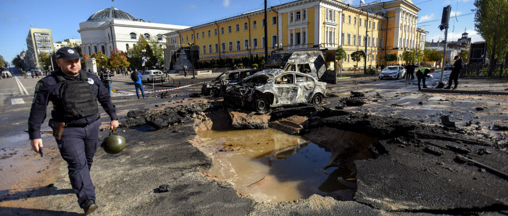epaselect epa10234190 A police officer (L) walks past destroyed cars at a damaged road after shelling in downtown Kyiv (Kiev), Ukraine, 10 October 2022. Explosions have been reported in several districts of the Ukrainian capital Kyiv on 10 October, with rescuers extinguishing fires and helping the victims among the civilian population, the State Emergency Service (SES) of Ukraine said. Russian troops entered Ukraine on 24 February 2022 starting a conflict that has provoked destruction and a humanitarian crisis.  EPA/OLEG PETRASYUK