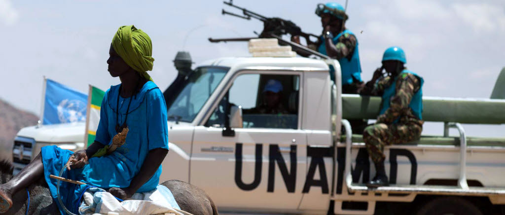 SWEDINT, NCGM
30 June 2014. Khor Abeche:
A woman rides a donkey loaded with water jerry cans, while UNAMID troops from Tanzania conduct a routine patrol in the camp for internally displaced persons (IDP) in Khor Abeche, South Darfur.
According to the local community, over 4,000 IDPs live inside a haven constructed by UNAMID at the vicinity of its compound since May 2014, following an attack on March 22, when 300 heavily armed men set fire to dozens of shelters and stole livestock belonging to the residents. The haven zone is 70,000 m2 and has watch towers with UNAMID military personnel deployed 24 hours, solar lights, two community centers and latrines.
Photo by Albert Gonzalez Farran, UNAMID