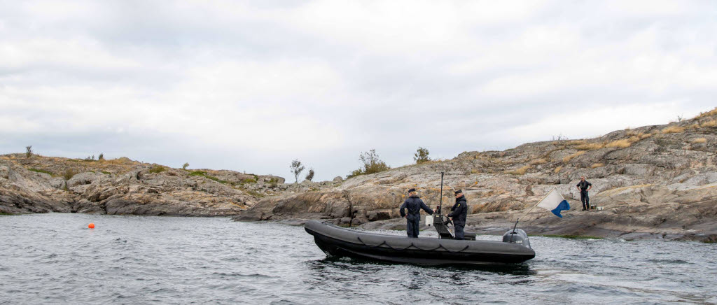 Dykare på båt undersöker sjömina.