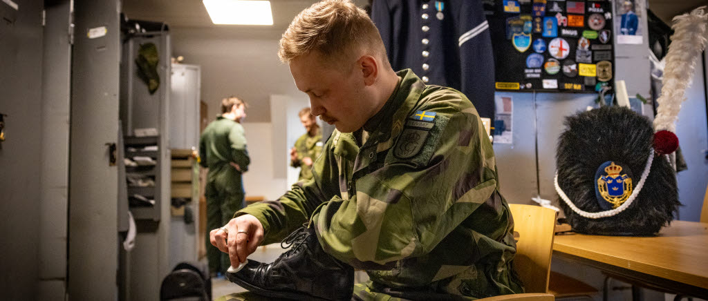 Soldate Albin Nilson Gres putsar skor inne på logomentet K1 Stockholm.