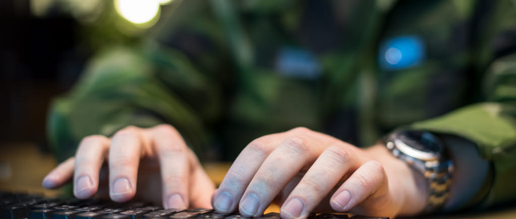 Cybersoldat skriver på ett tangentbord vid dator.