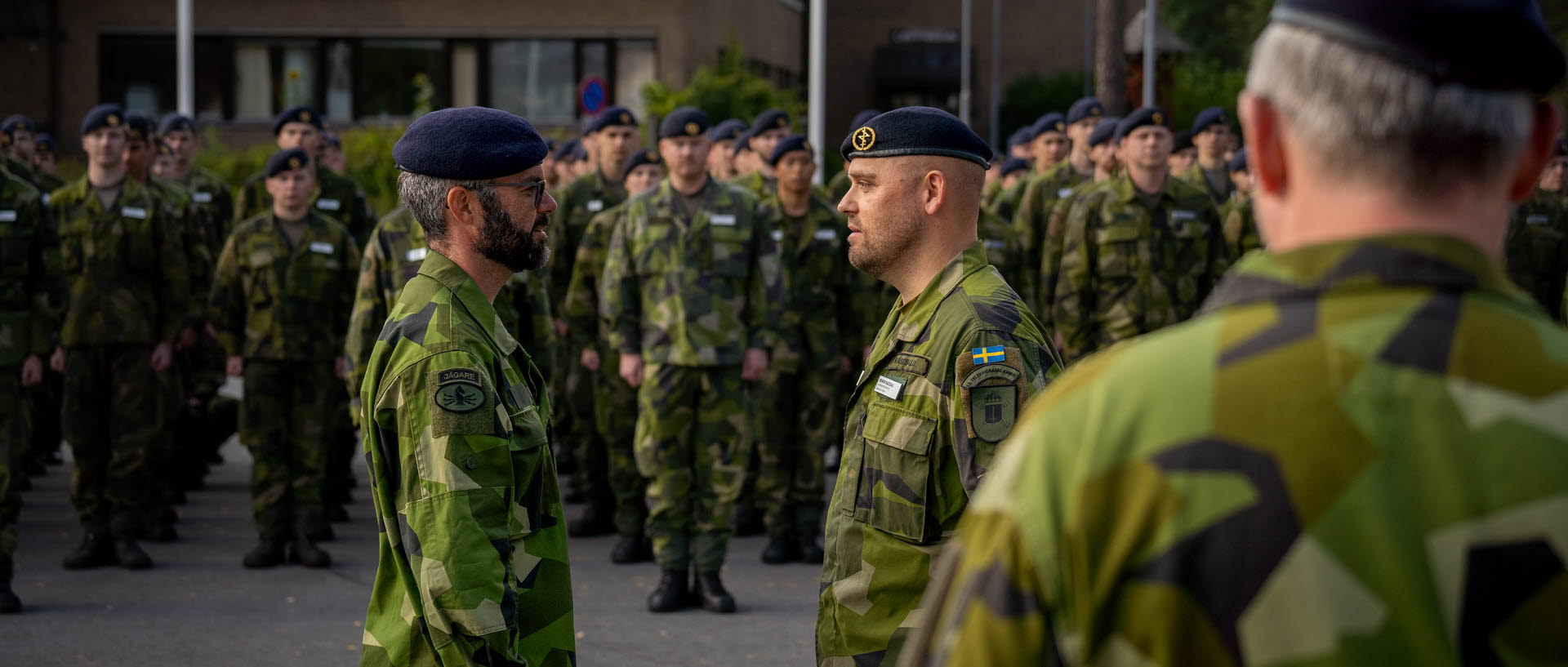 Två män klädda i grön uniform och svart basker står mittemot varandra.