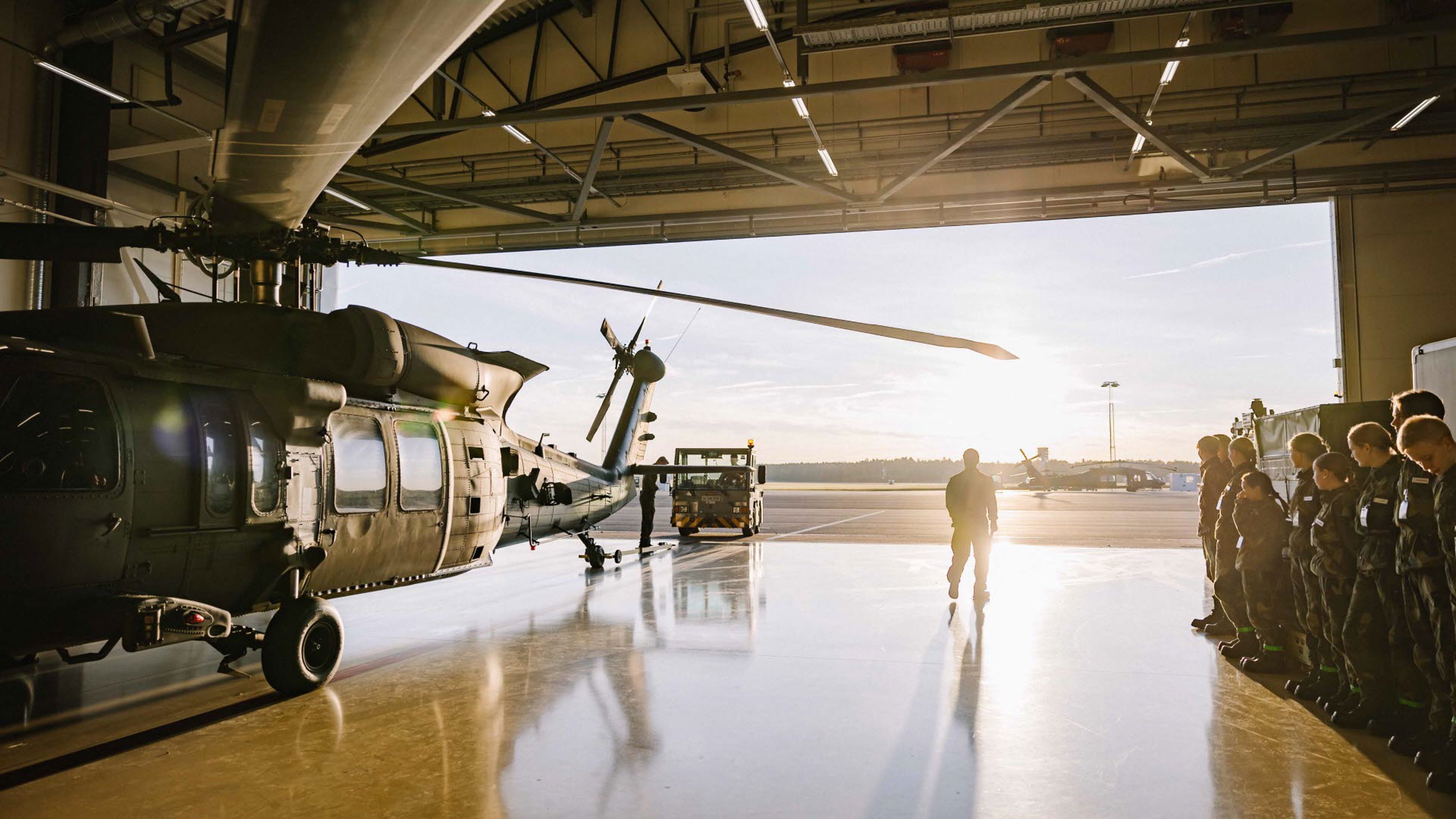 Prao-elever på Helikopterflottiljen står uppställda framför en helikopter 16 i en hangar på Malmen i Linköping.