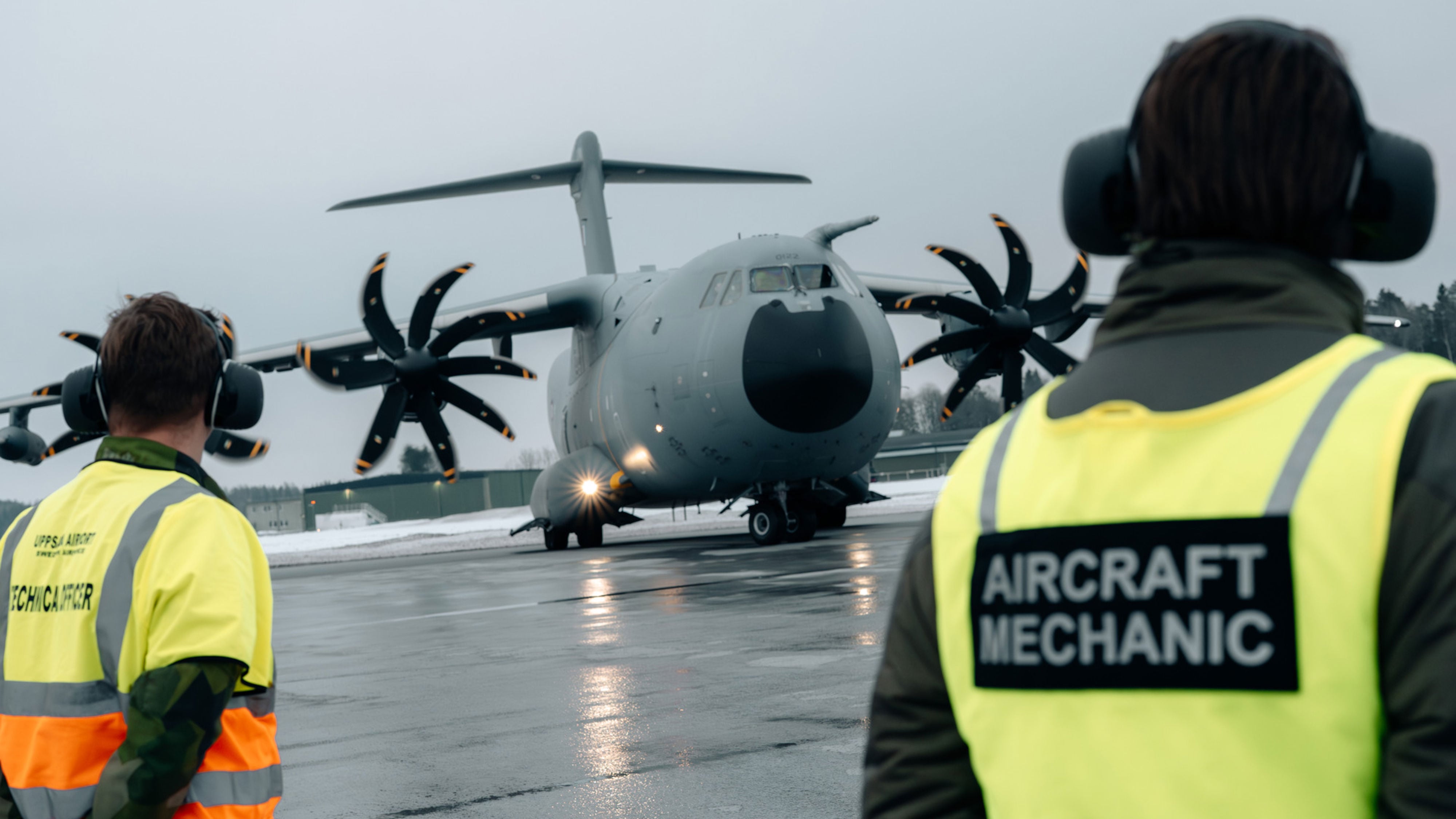 Flygplatspersonal tar emot militärt transportflyg