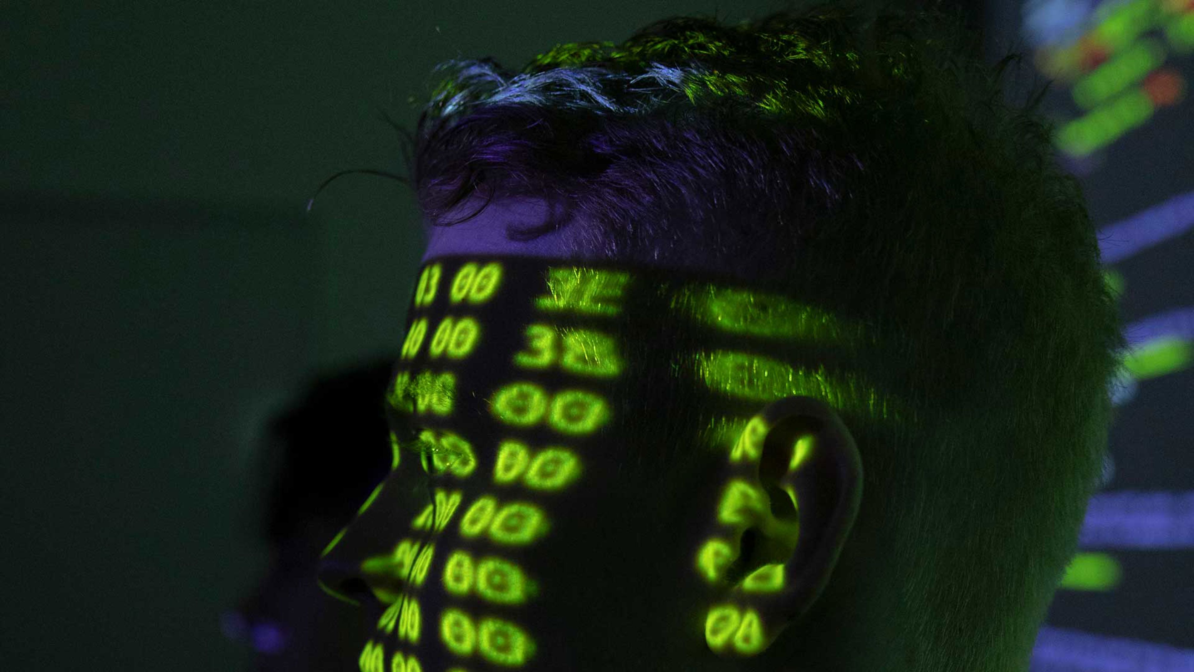 Del av ansiktet på en man med massa siffror som reflekterar från en skärm på hans ansikte