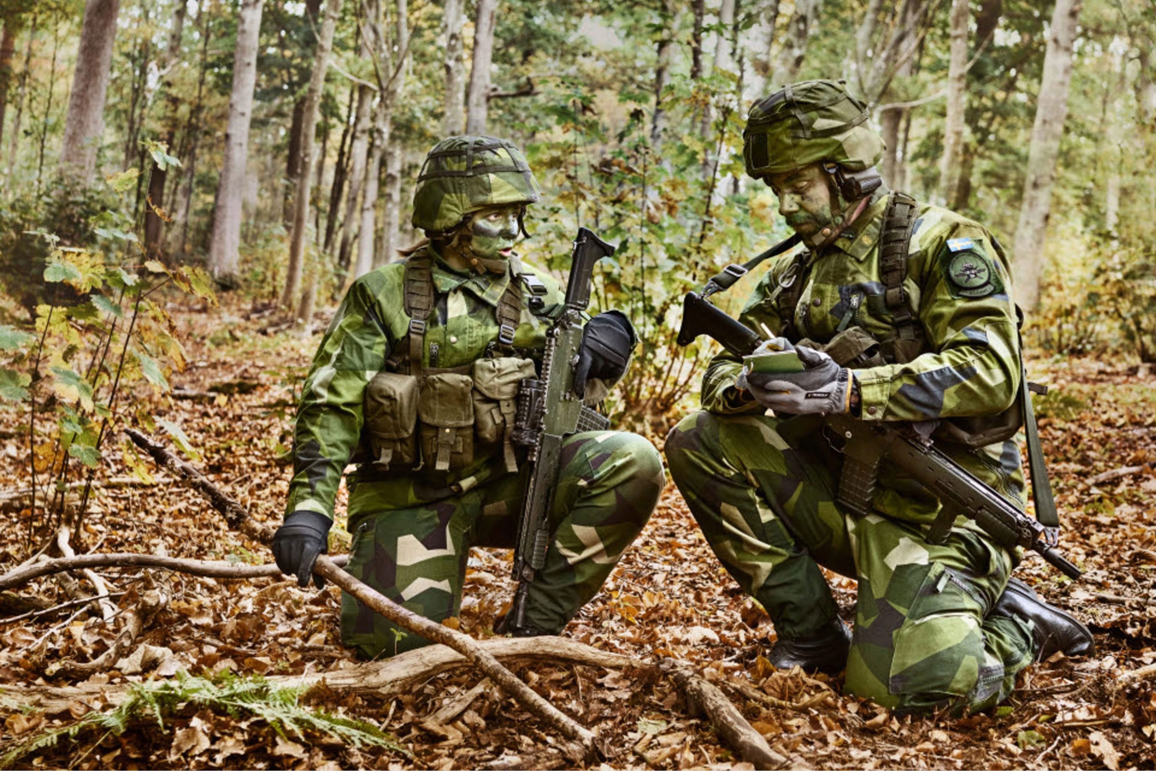 Svenska soldater i fält antecknar i knästående ställning.