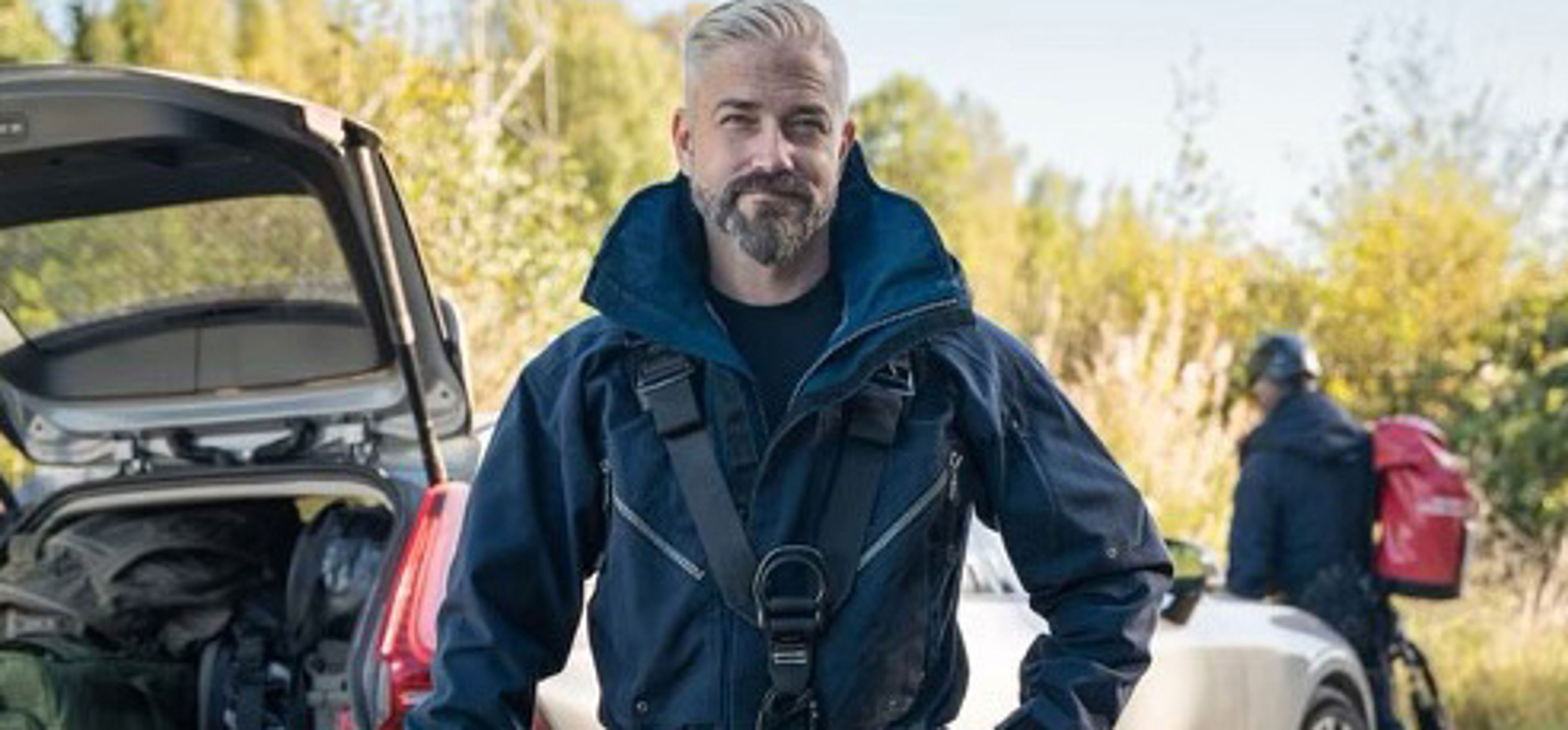 Utrustad teleingenjör poserar framför sin bil.