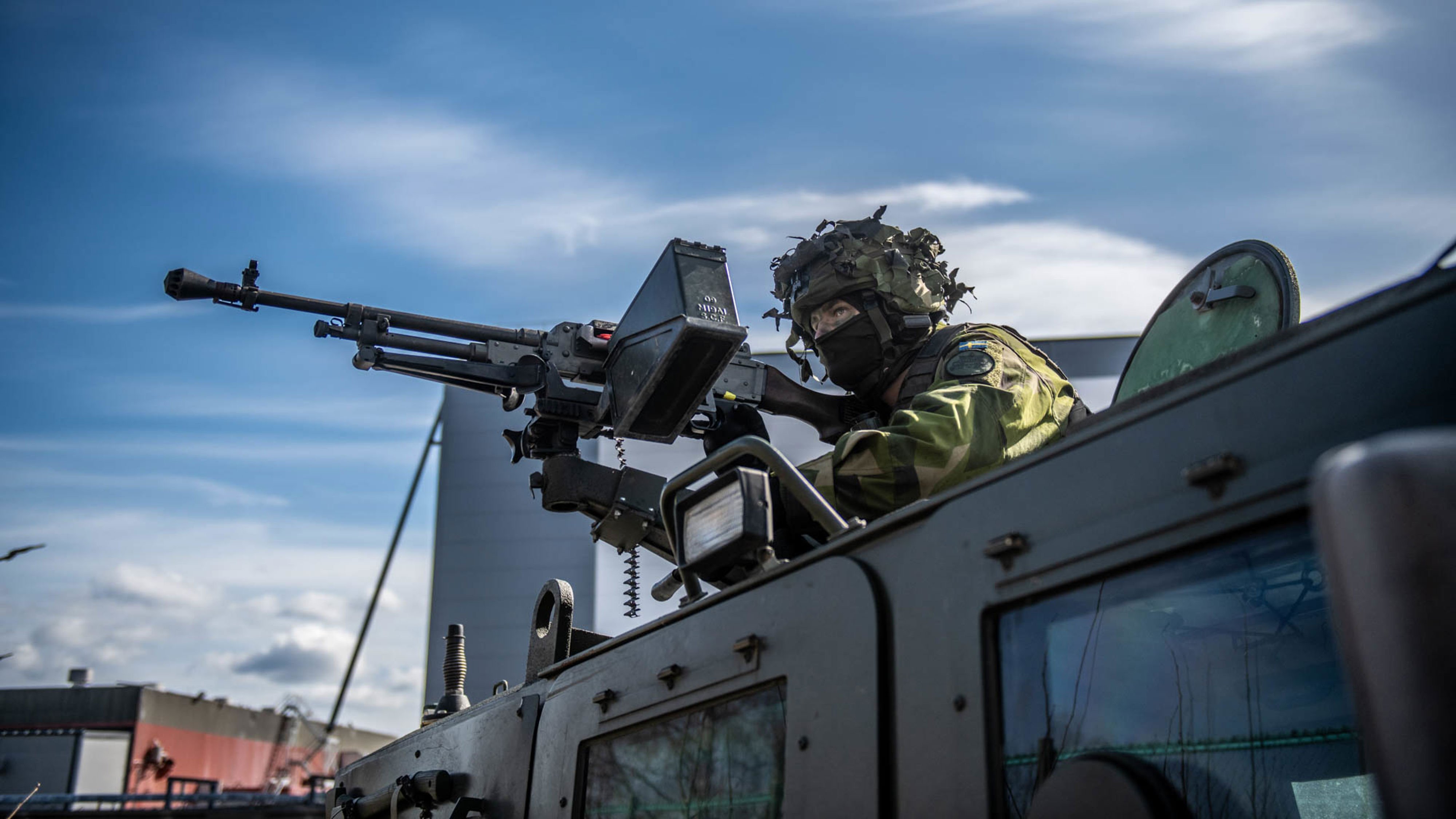 Soldat står vid en vapenstation på ett fordon.