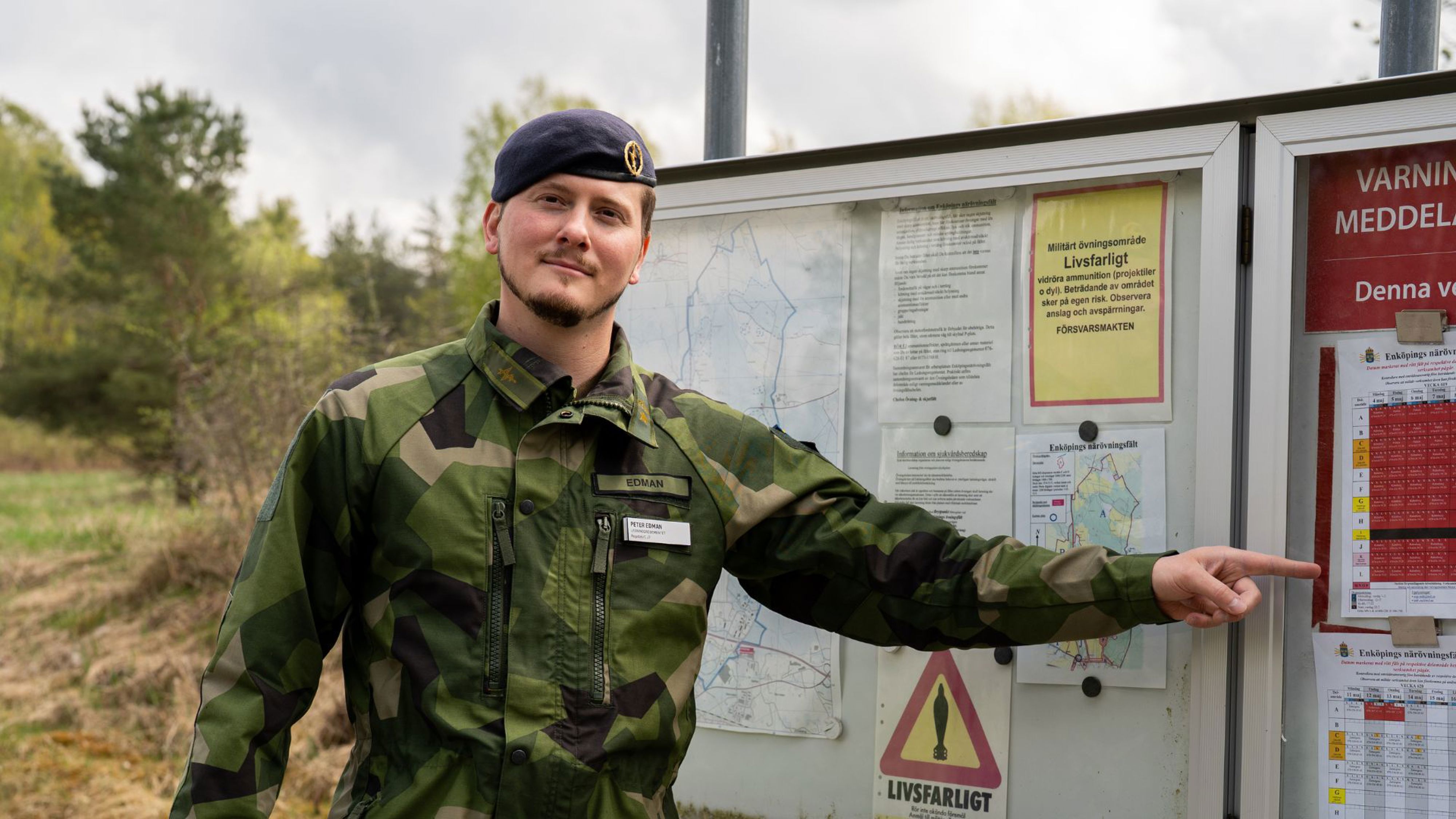 Man i militär uniform framför en informationstavla.
