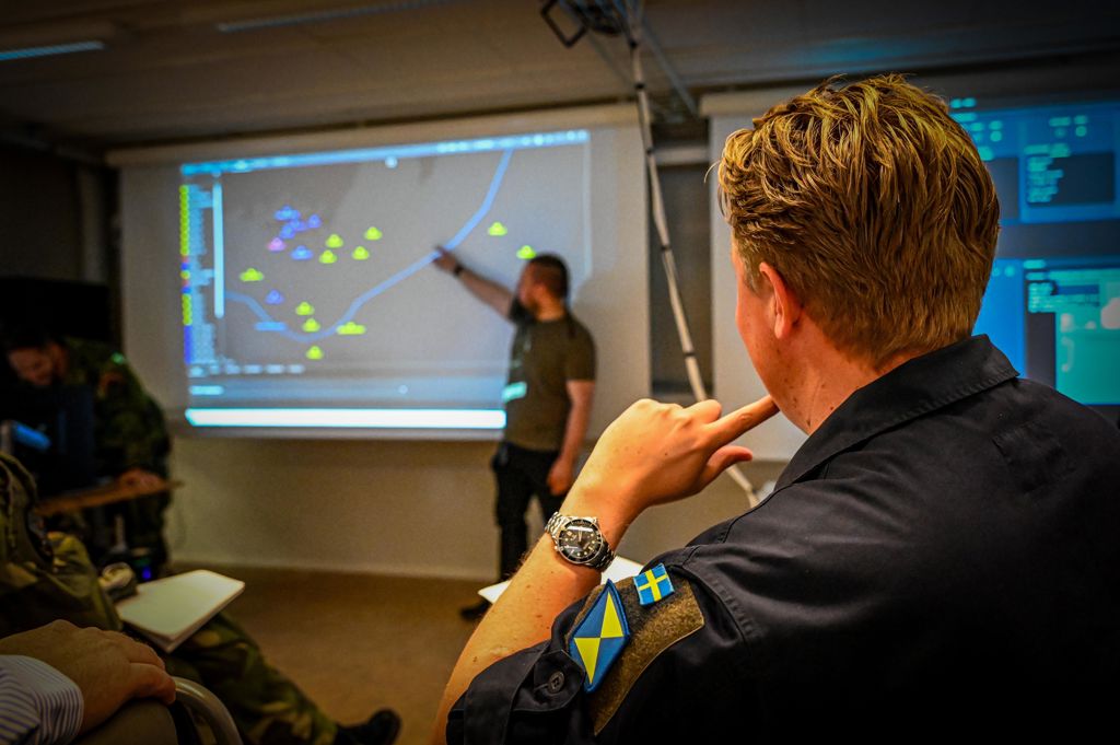 Militärklädda män fotograferade bakifrån i klassrum under workshop på luftstridsskolan.