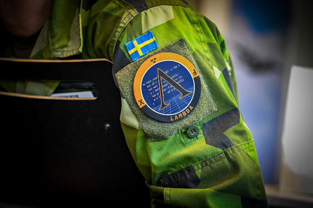 Emblem på militärklädd arm med bokstäverna LAMBDA på.