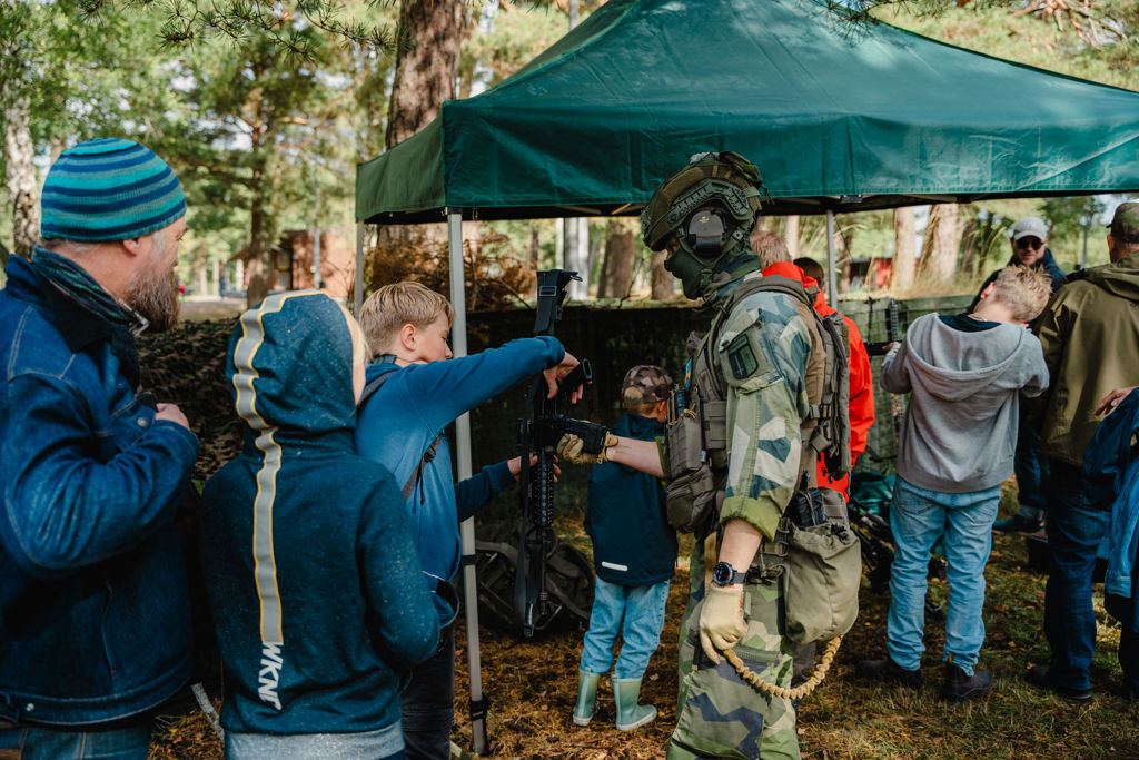 En soldat visar upp ett vapen för en grupp människor