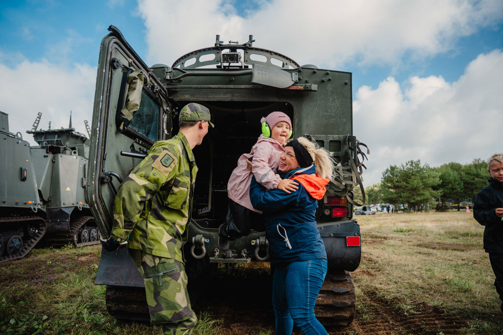 En soldat hjälper en kvinna att lyfta ner ett litet barn från ett militärt fordon