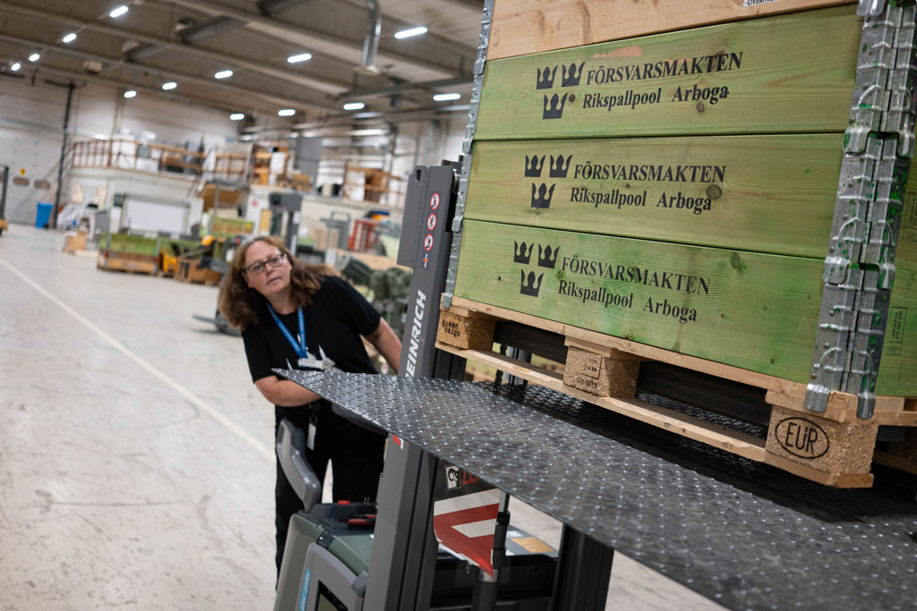 Kvinna lyfter lastpallar med truck.