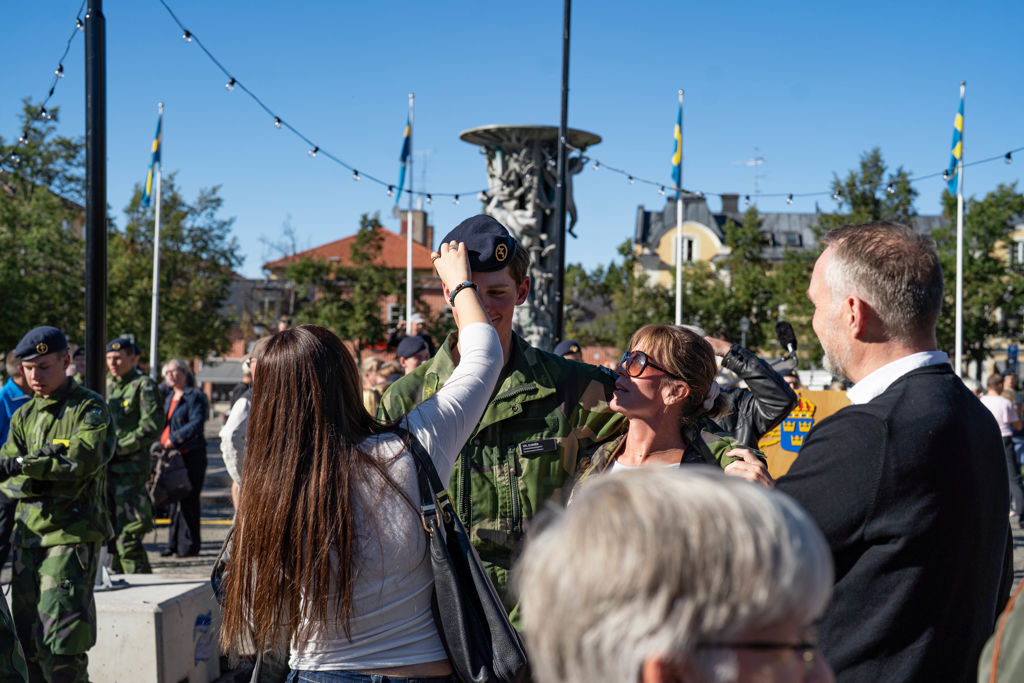 Tjej rättar till baskern på värnpliktig.