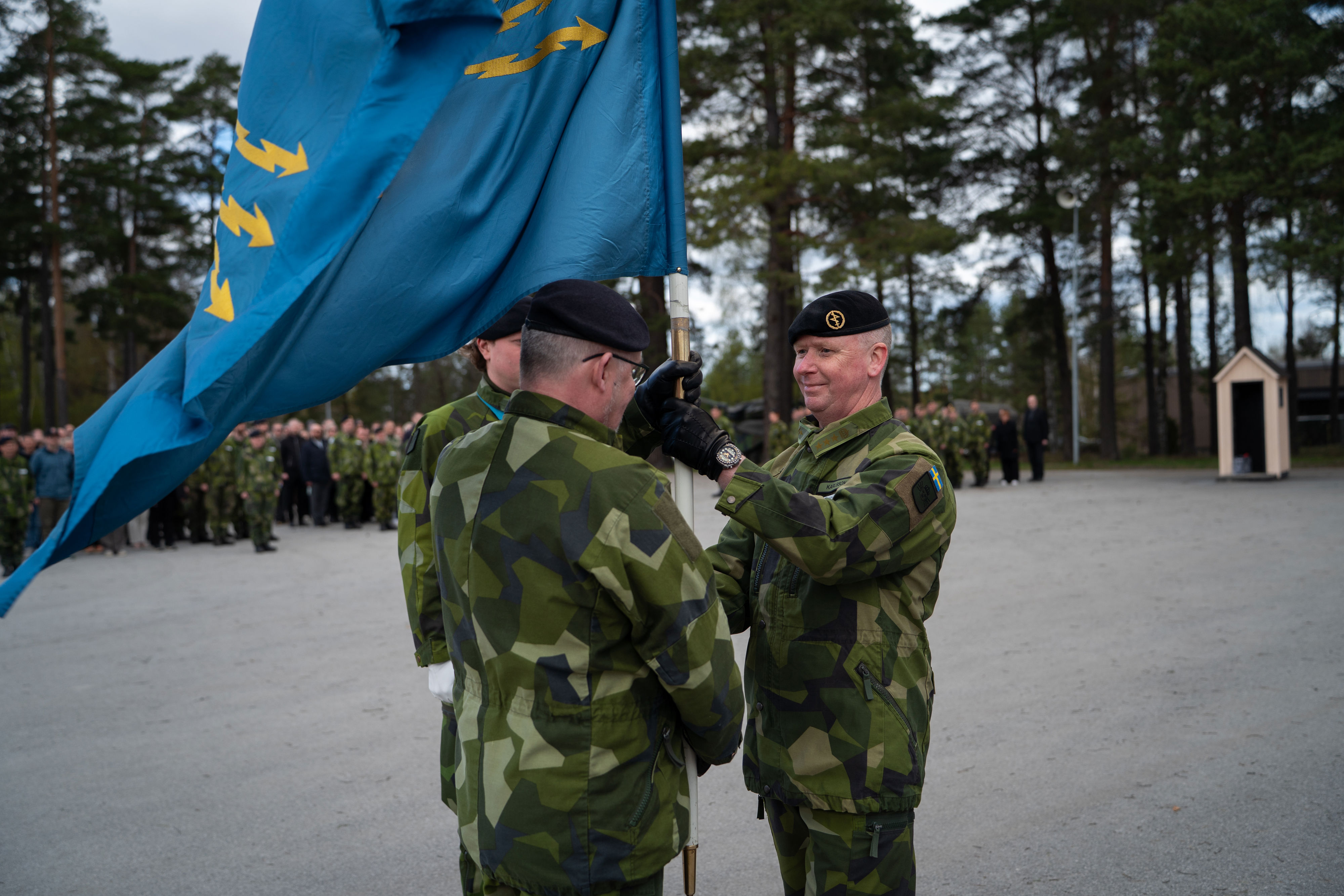 Rickard Karlsson-Lindquist tar över Ledningsregementets fana från avgående chef Per Nilsson.