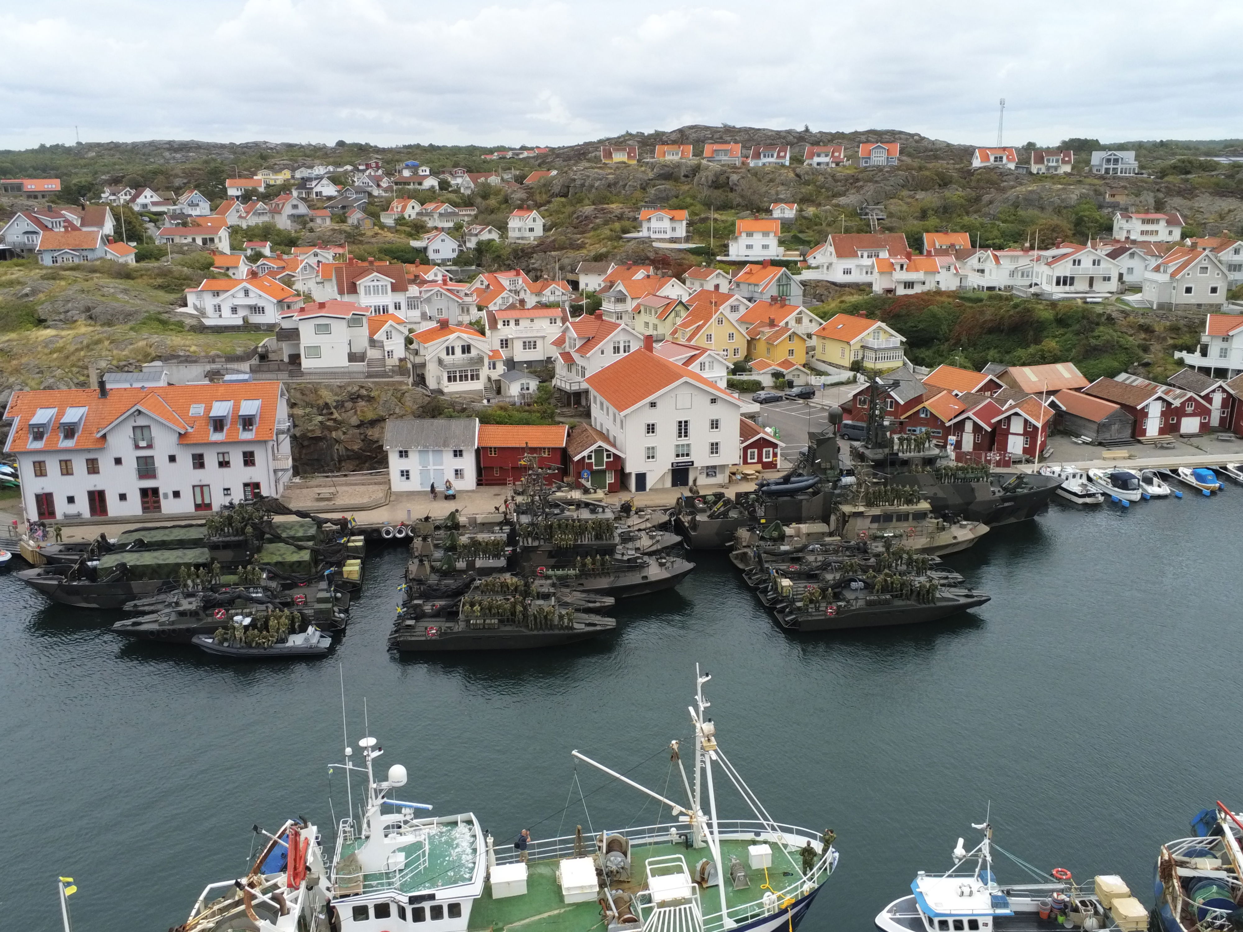 Drönarbild över Lysekils hamn med ett femtontal militära fartyg förtöjda.