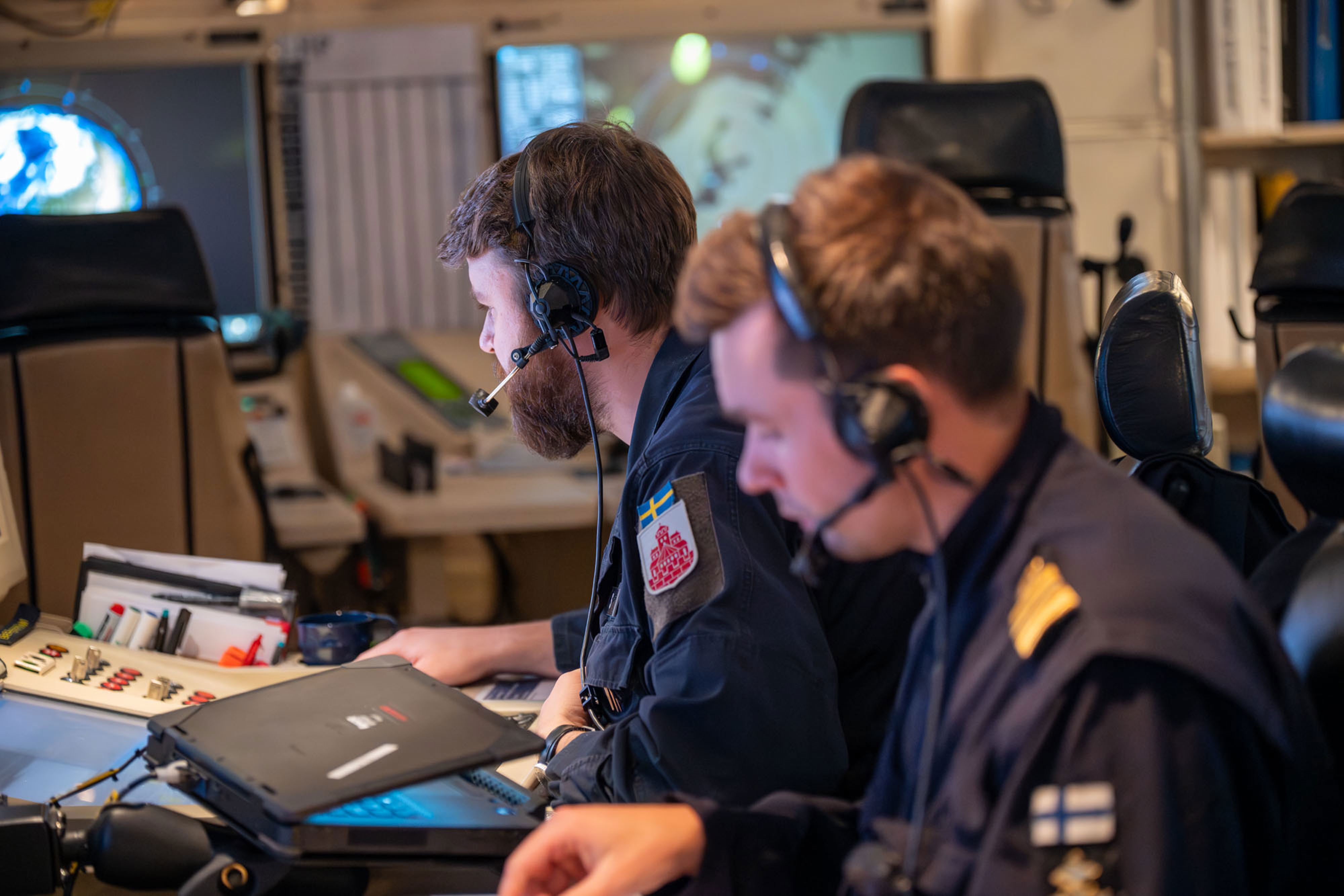 Svenska och finska officerare jobbar sida vid sida i stridsledningscentralen på HMS Helsingborg.