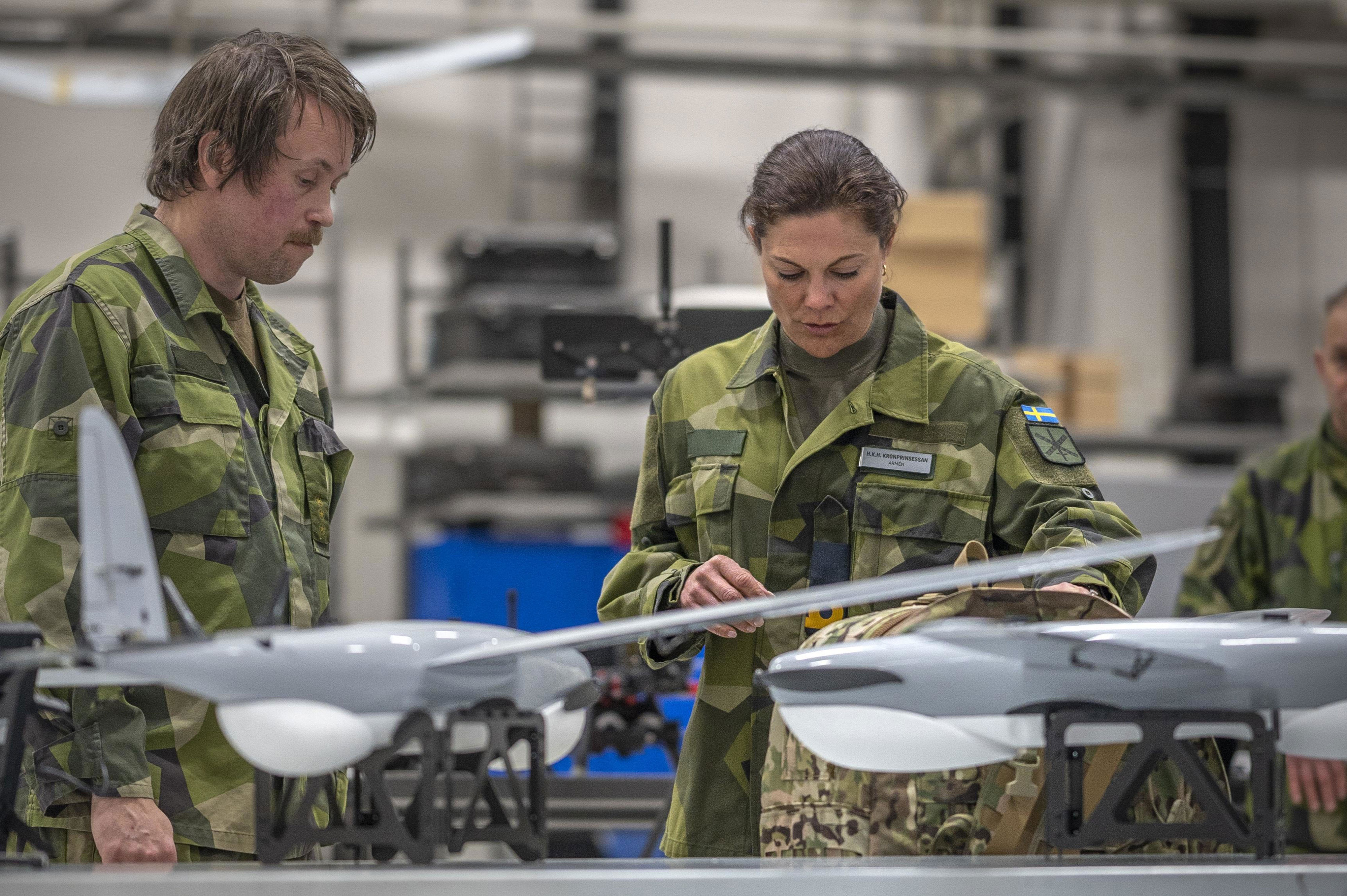 Kronprinsessan Victoria står framför ett bord med drönare och drönarutrustning.