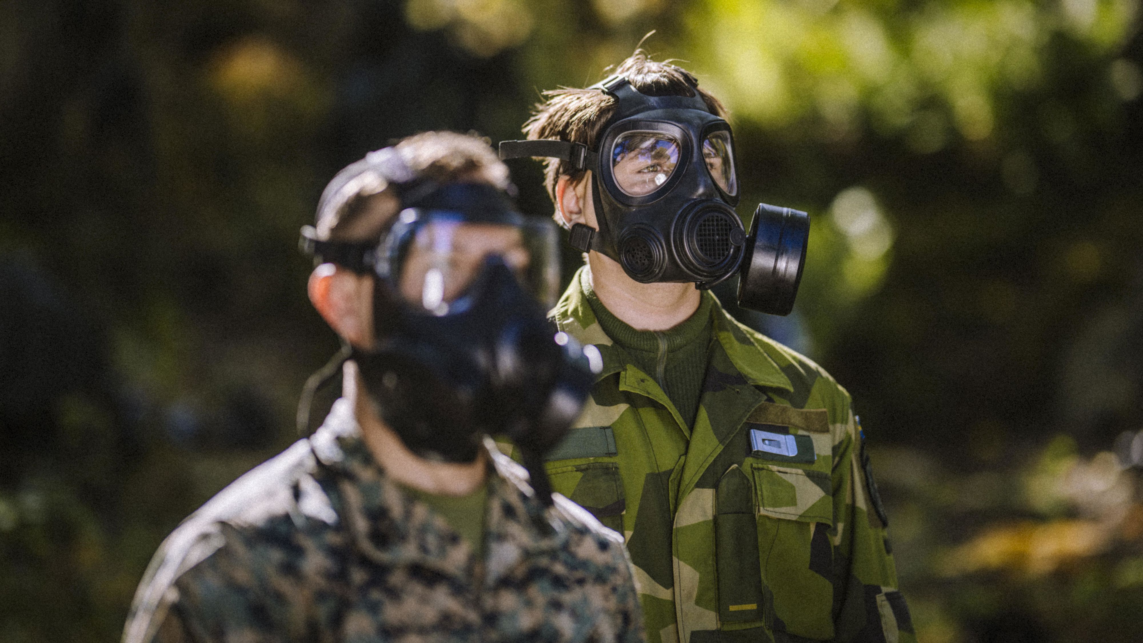 Två män i militäruniform och gasmask.