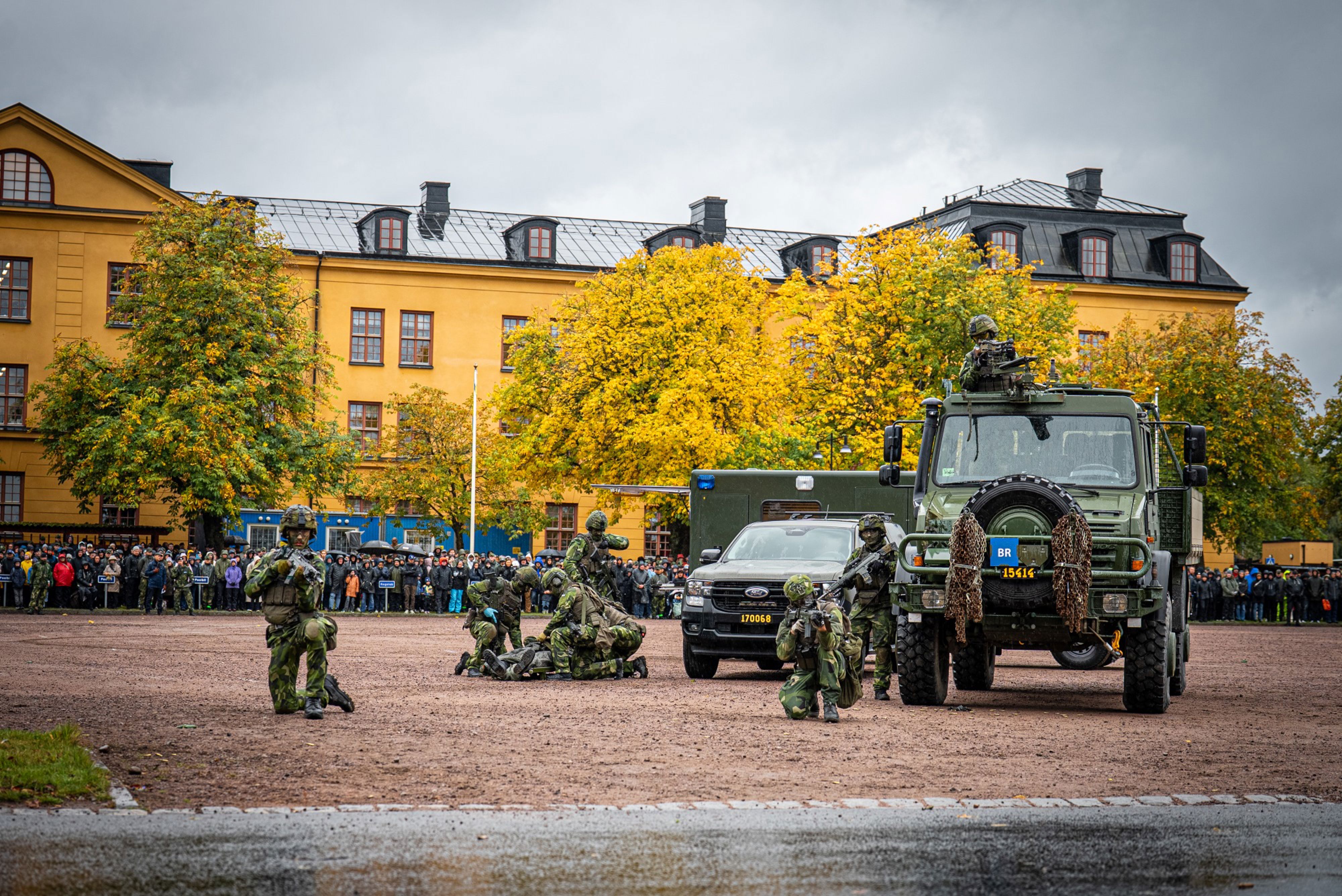 Några soldater och militära fordon utanför gul byggnad