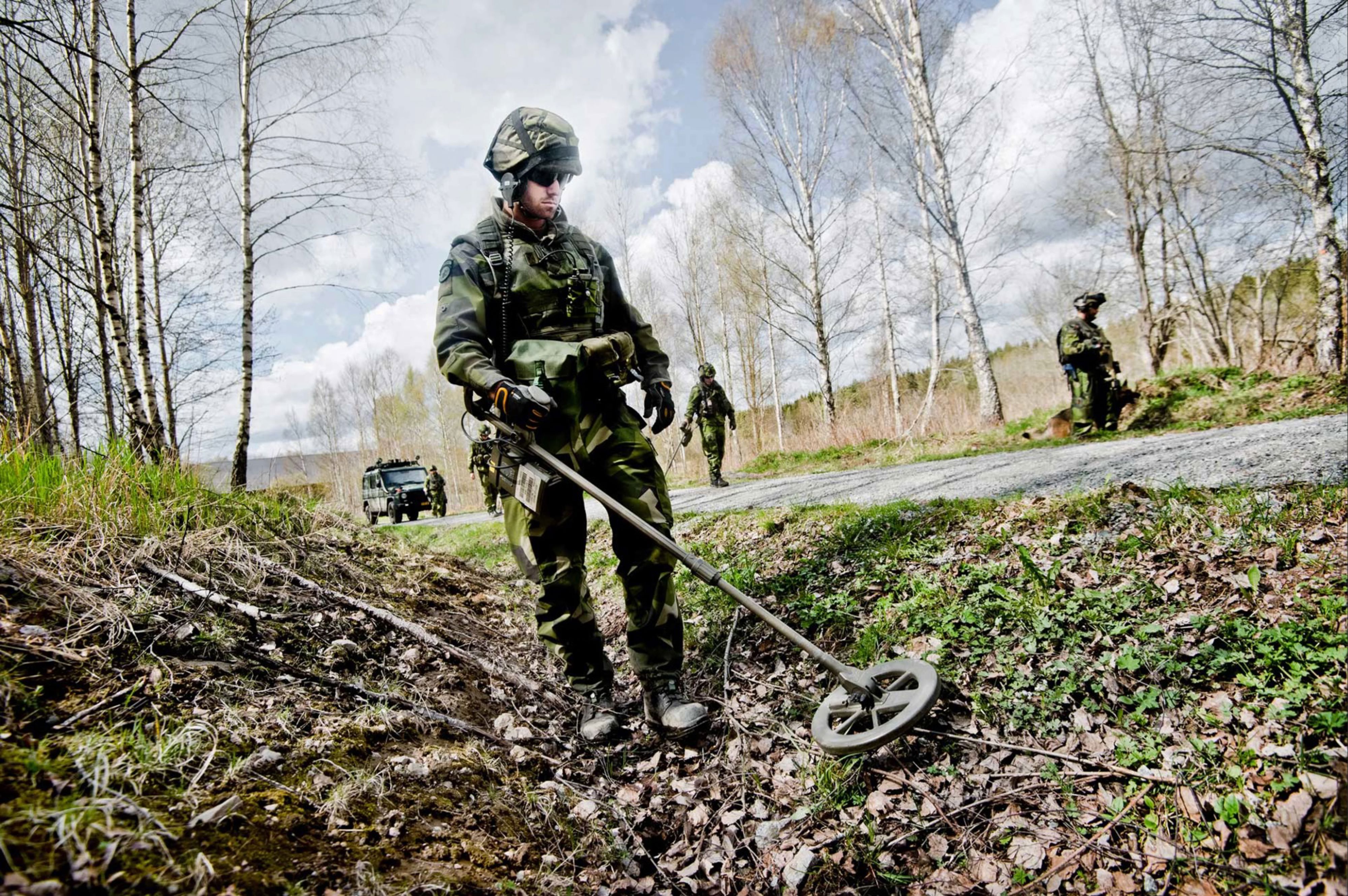 Soldat som skannar efter minor ute i naturen.