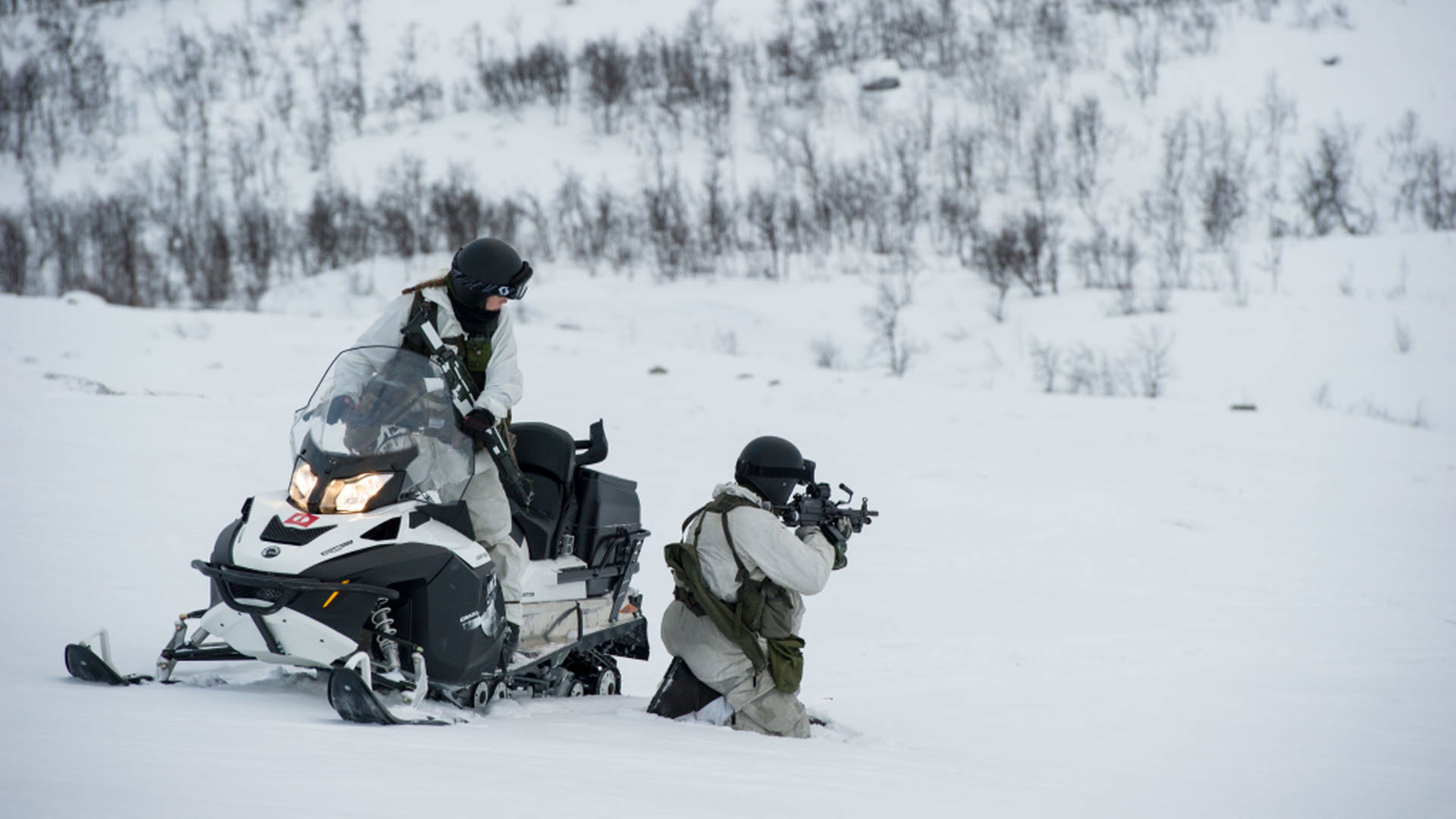Två soldater vid en snöskoter i skogen.