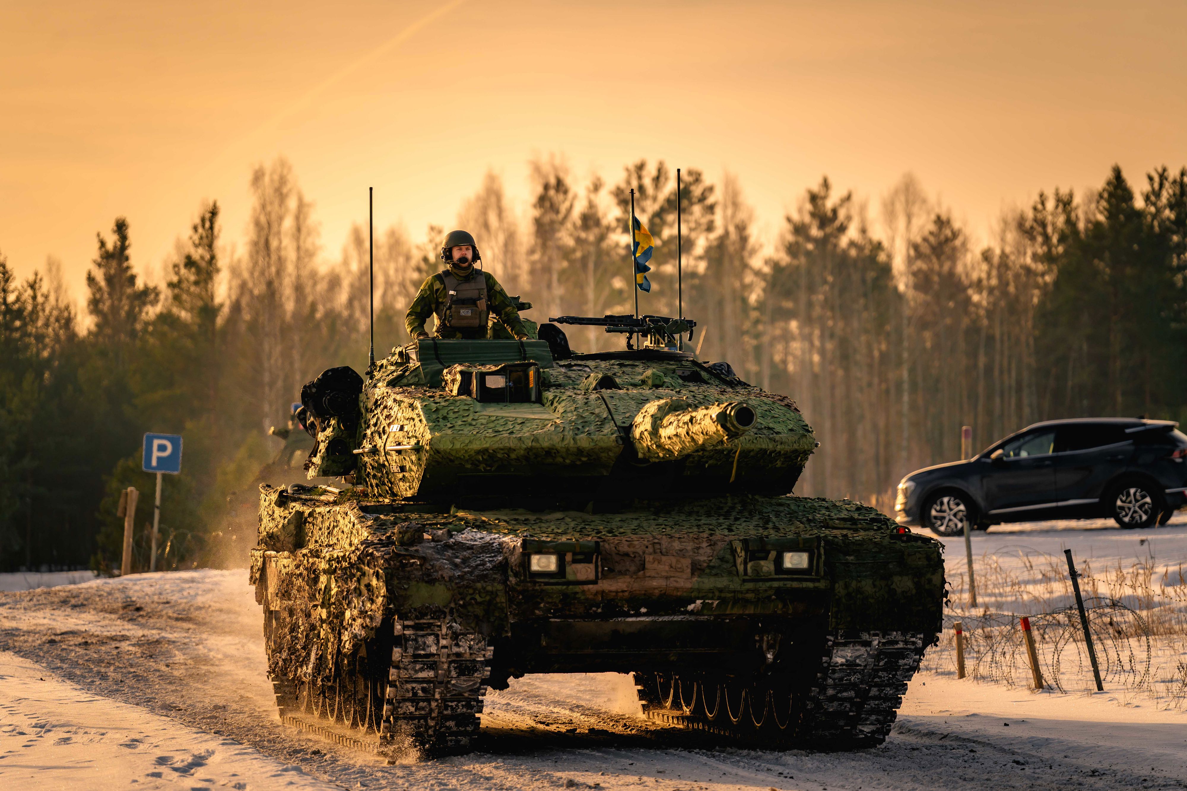 En soldat på en pansarvagn i solnedgången nära en skog