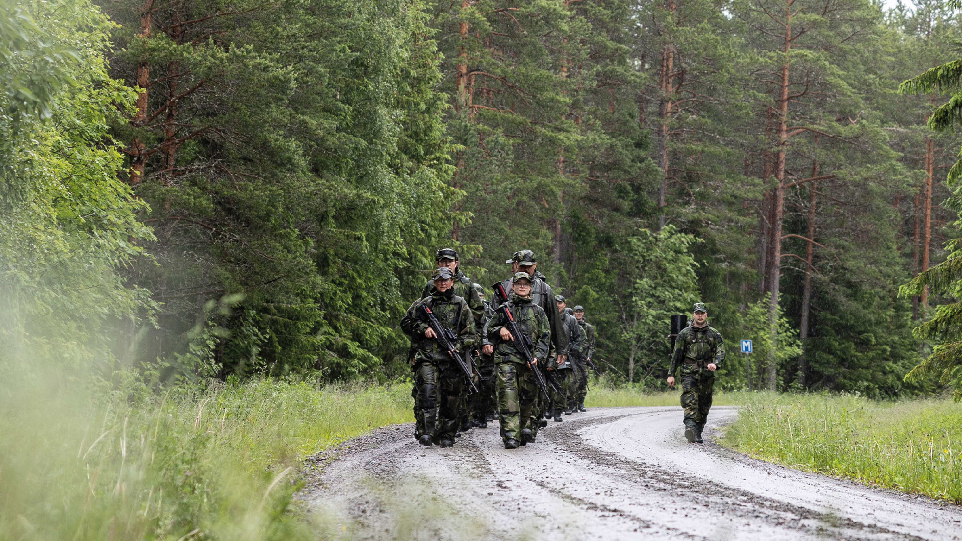 Soldater går på rad på en grusväg i skogen.