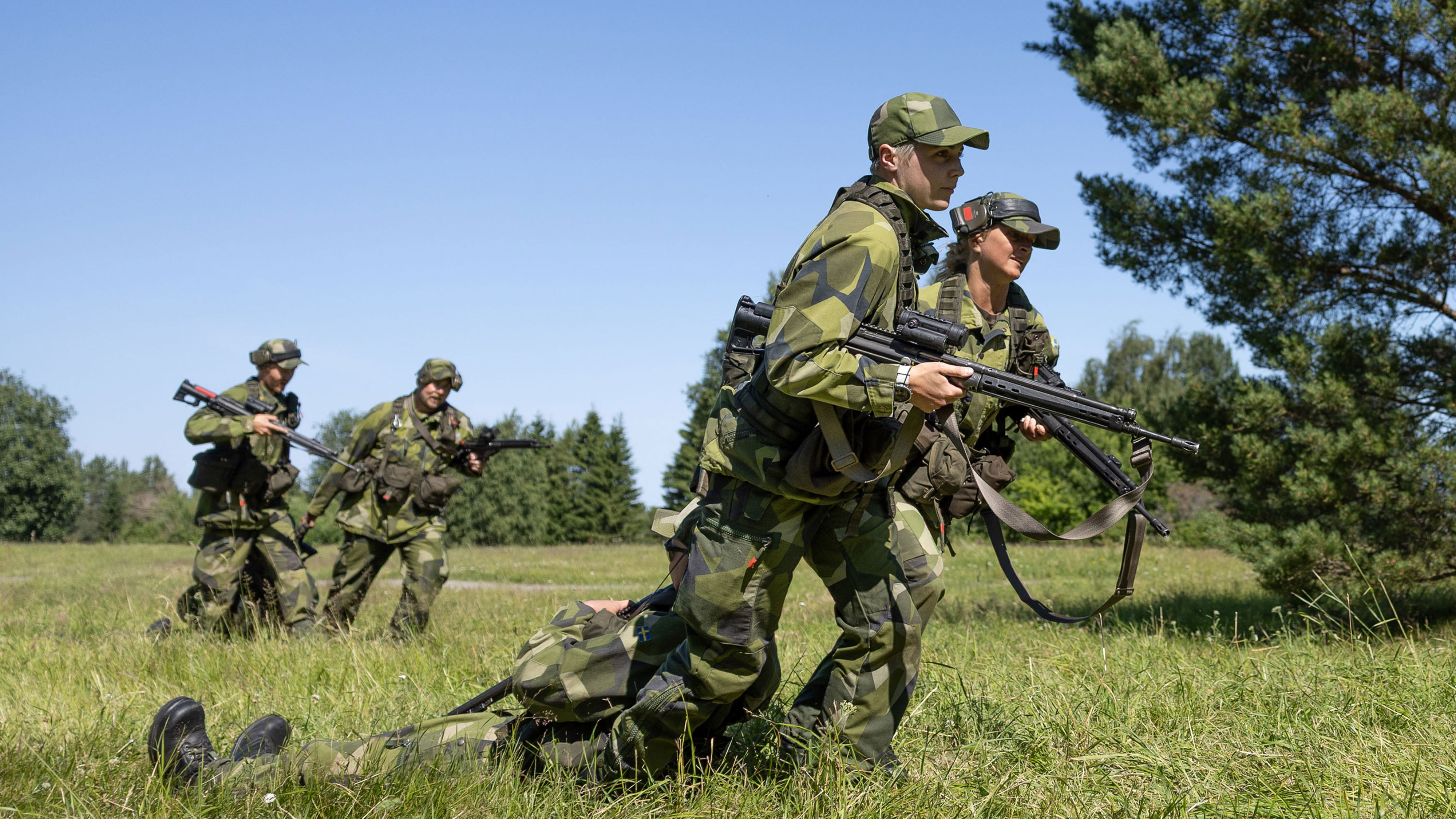 Soldater drar en annan skadat soldat över ett gräsfält.
