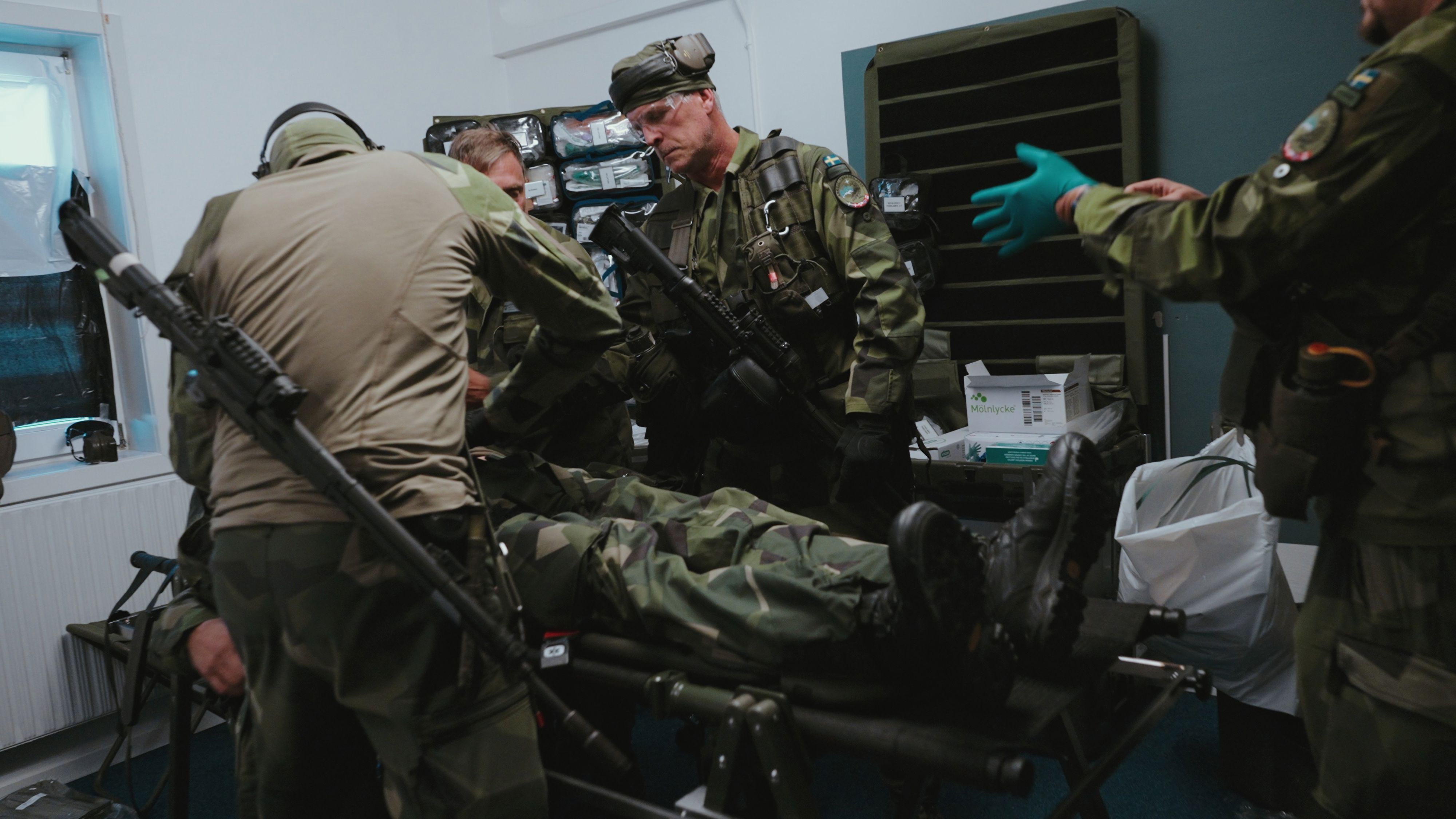 Soldater omhändertar skadad soldat på bår.